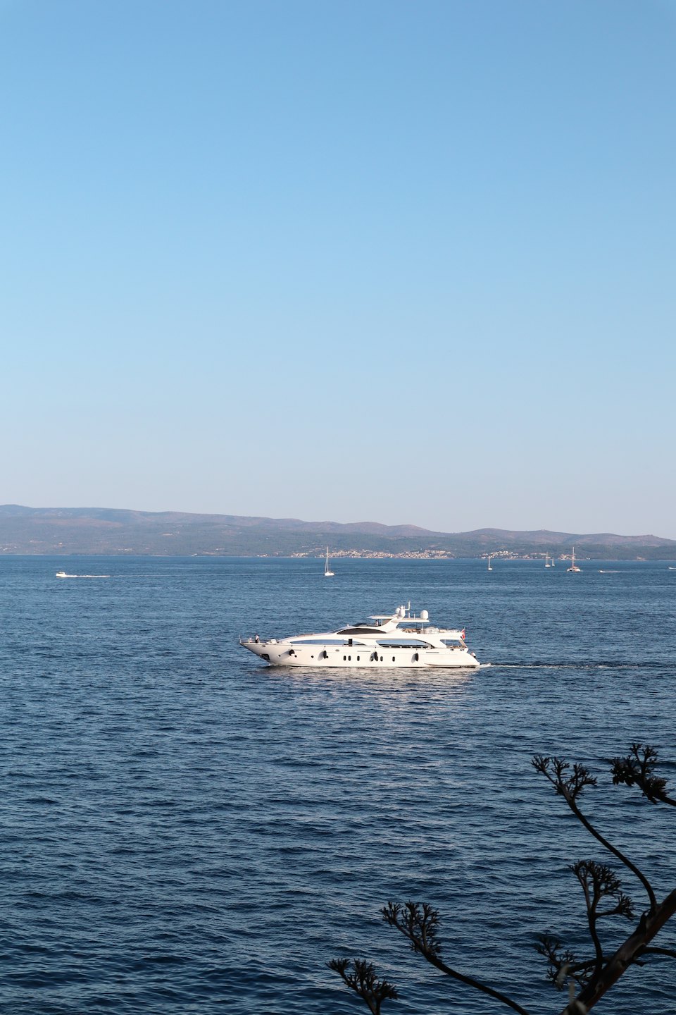 Yacht di lusso che naviga su acque blu calme vicino alla costa.