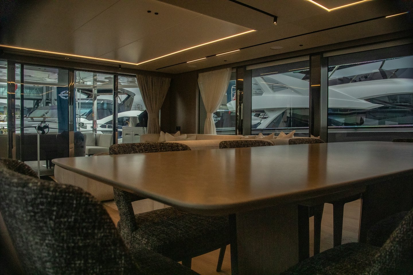 Interno di uno yacht di lusso con tavolo da pranzo, divani e grandi finestre.