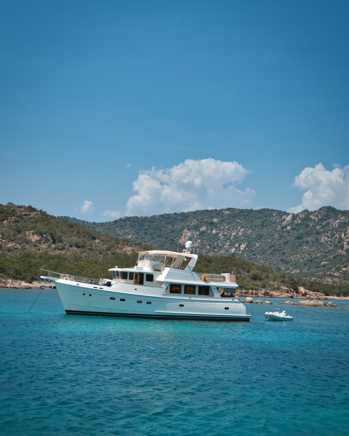 Uno yacht di lusso ancorato in acque turchesi limpide vicino a una costa.